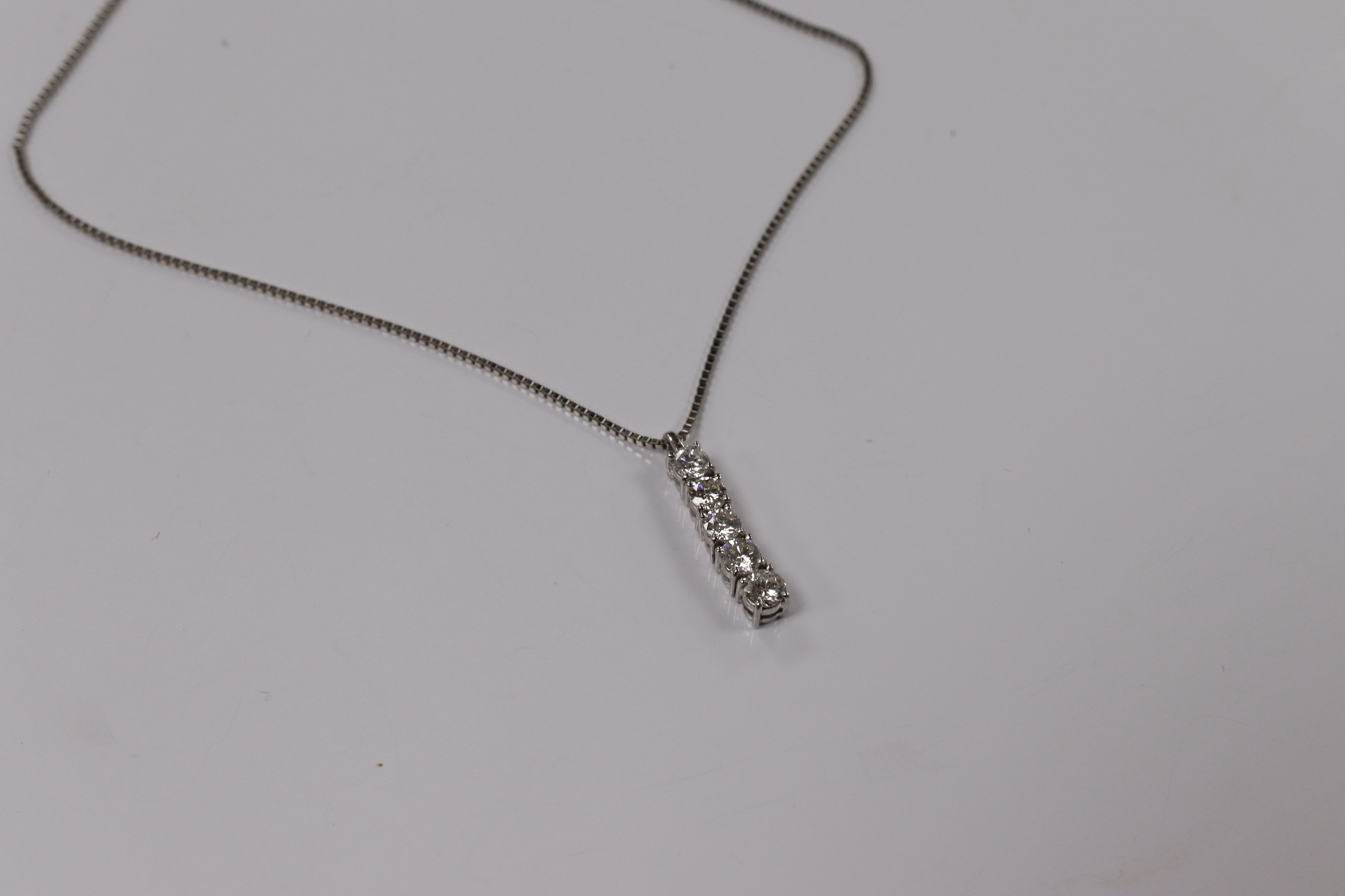 A modern white metal (stamped PT900) and five stone diamond set line pendant, on white metal (stamped pt850), overall 49cm, gross weight 4.9 grams. Condition - fair to good